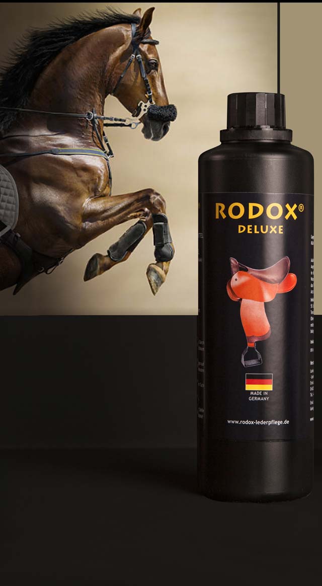 Ein brauner Hengst springt ins Bild. Der Hintergrund des Bildes ist schwarz. Im Vordergrund steht eine Flasche von RODOX® Pflege- und Reinigungsmittel für Leder-Pferdesättel. Die Überschrift RODOX DELUXE.